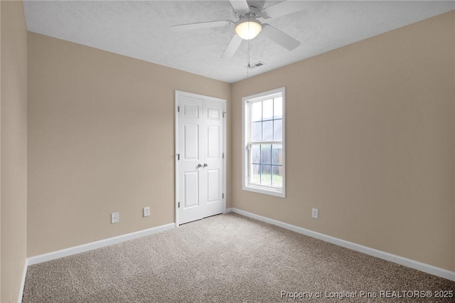 unfurnished room with carpet, baseboards, ceiling fan, and a textured ceiling