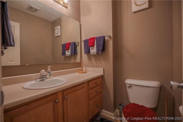bathroom with visible vents, toilet, and vanity