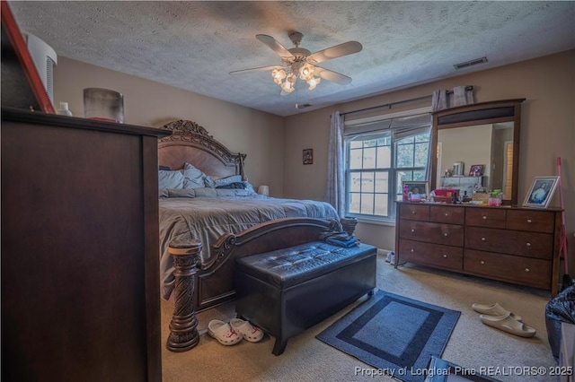carpeted bedroom featuring a ceiling fan, a textured ceiling, and visible vents