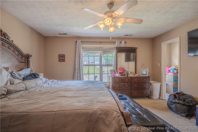 bedroom featuring carpet floors, a ceiling fan, a textured ceiling, and visible vents