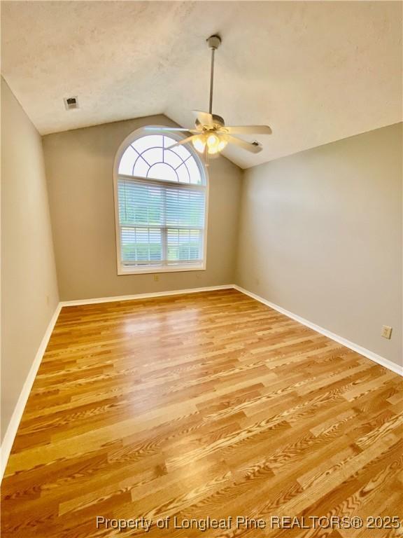 unfurnished room with visible vents, a ceiling fan, lofted ceiling, and light wood-type flooring