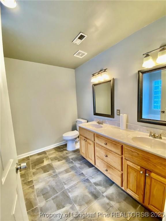 full bath featuring a sink, toilet, double vanity, and visible vents