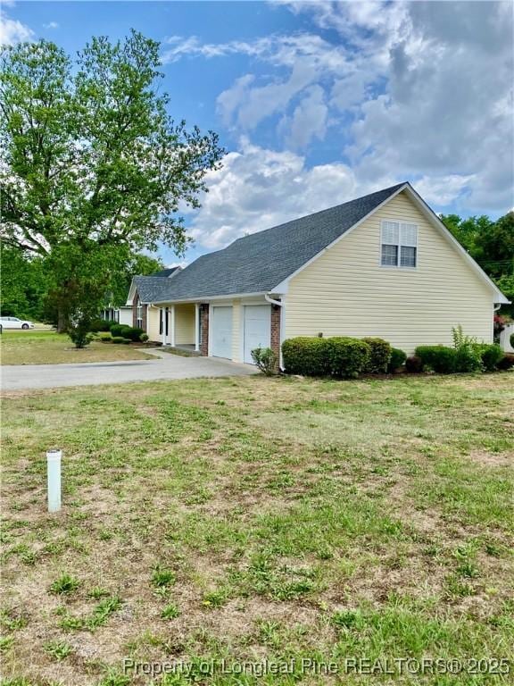 view of property exterior featuring a lawn, an attached garage, and driveway
