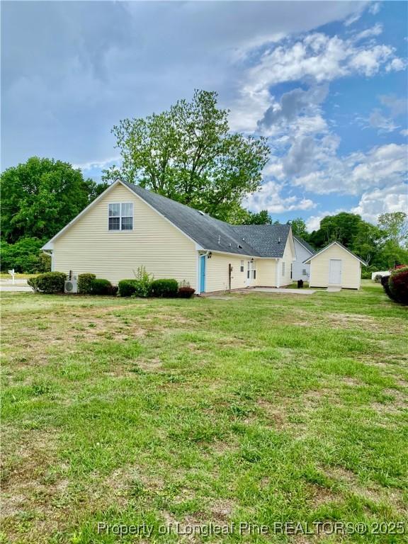 view of side of property with a lawn and an outbuilding