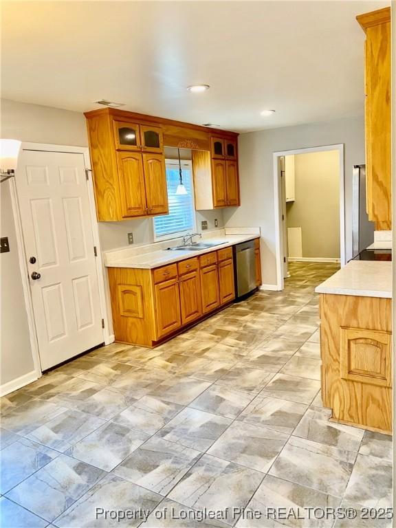 kitchen with light countertops, baseboards, a sink, and dishwasher