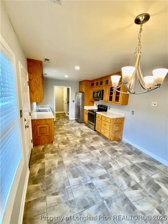 kitchen featuring brown cabinets, an inviting chandelier, a sink, stainless steel appliances, and recessed lighting