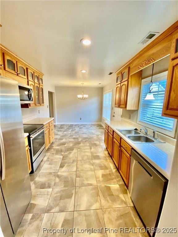 kitchen featuring an inviting chandelier, a sink, hanging light fixtures, and stainless steel appliances