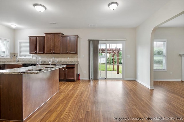 153 Dairy Ct, Raeford, NC 28376 - kitchen with light wood-type flooring, light stone countertops, decorative backsplash, and arched walkways
