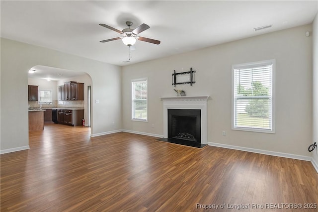 153 Dairy Ct, Raeford, NC 28376 - unfurnished living room with a ceiling fan, plenty of natural light, dark wood-style flooring, and a fireplace with raised hearth