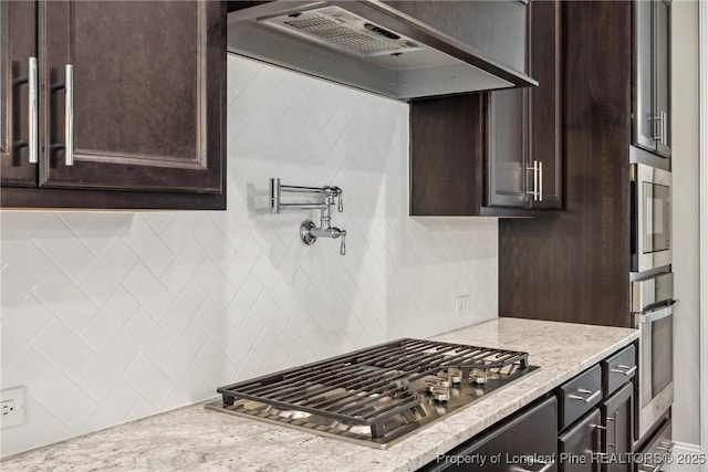 405 Gilpin Way, Cary, NC 27519 - kitchen featuring stainless steel appliances, custom range hood, dark brown cabinetry, tasteful backsplash, and light stone counters