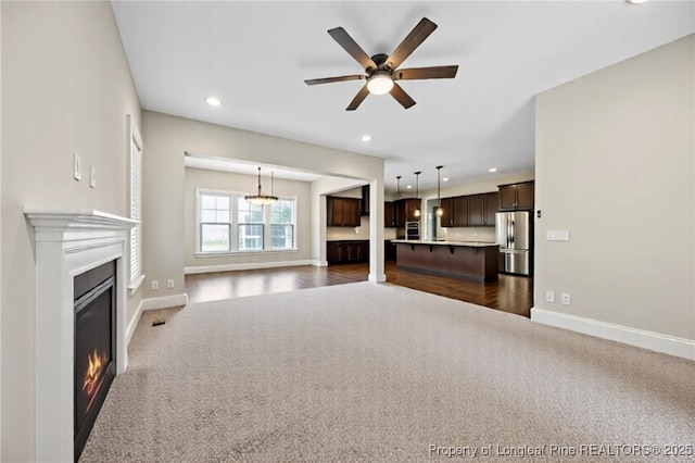 405 Gilpin Way, Cary, NC 27519 - unfurnished living room featuring dark colored carpet, a glass covered fireplace, baseboards, a ceiling fan, and recessed lighting