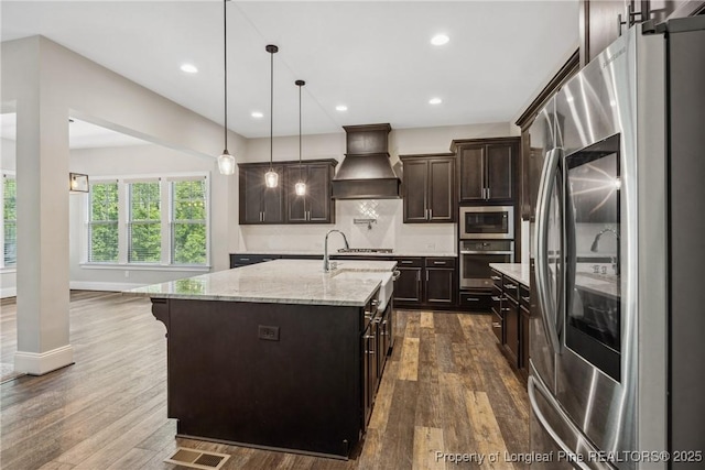 405 Gilpin Way, Cary, NC 27519 - kitchen featuring appliances with stainless steel finishes, custom exhaust hood, dark brown cabinetry, light stone countertops, and backsplash