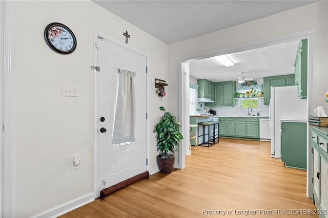 1963 Seabrook School Rd, Fayetteville, NC 28312 - kitchen featuring green cabinetry, white appliances, a sink, a textured ceiling, and light wood finished floors