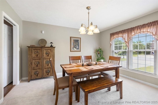 dining area with light colored carpet, a chandelier, and baseboards