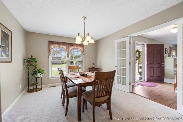 carpeted dining area with a chandelier and baseboards