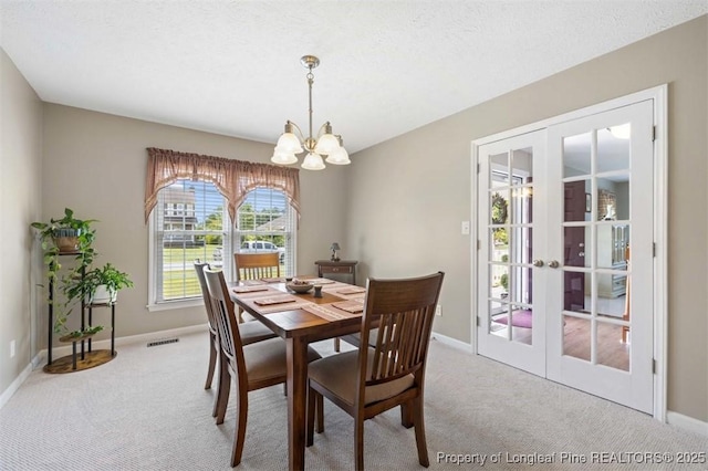 carpeted dining area featuring french doors, a chandelier, and baseboards