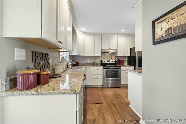 kitchen featuring electric range, under cabinet range hood, wood finished floors, white cabinets, and recessed lighting
