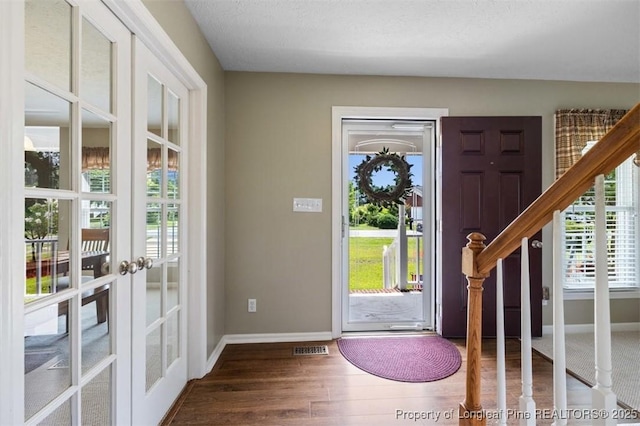 entrance foyer featuring baseboards, wood finished floors, french doors, and stairway
