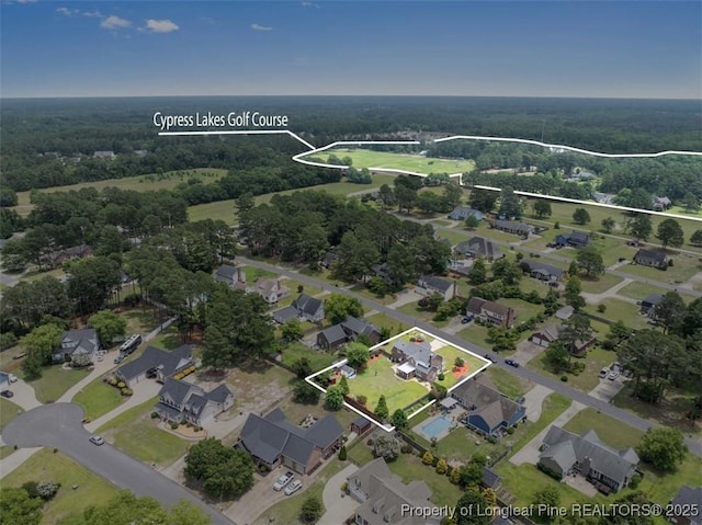 aerial view of property's location featuring nearby suburban area and a heavily wooded area
