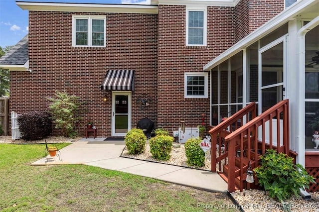 view of front of house featuring brick siding, a patio area, a front lawn, and a sunroom