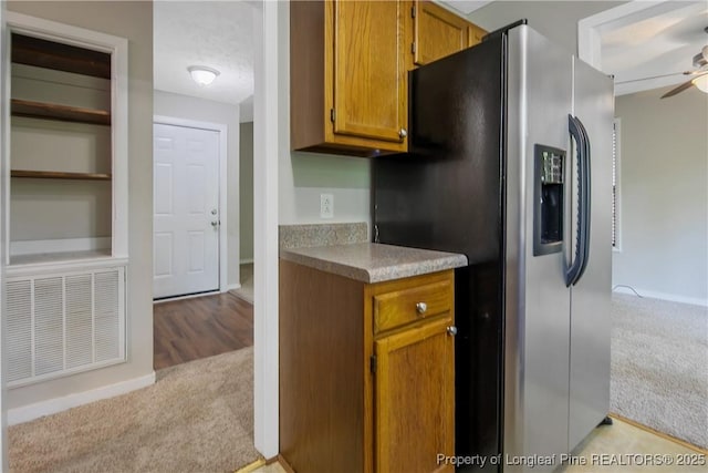 303 Whipple Tree Ln, Fayetteville, NC 28314 - kitchen with stainless steel refrigerator with ice dispenser, light carpet, a ceiling fan, brown cabinetry, and light countertops