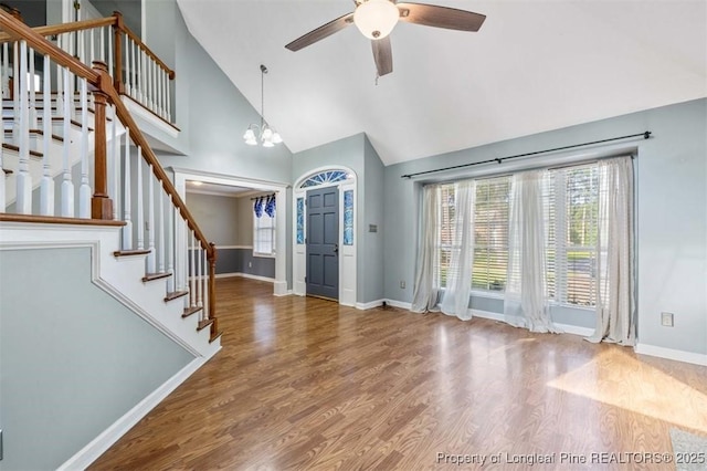 7616 Spurge Dr, Fayetteville, NC 28311 - unfurnished living room featuring high vaulted ceiling, ceiling fan, stairs, wood finished floors, and a chandelier