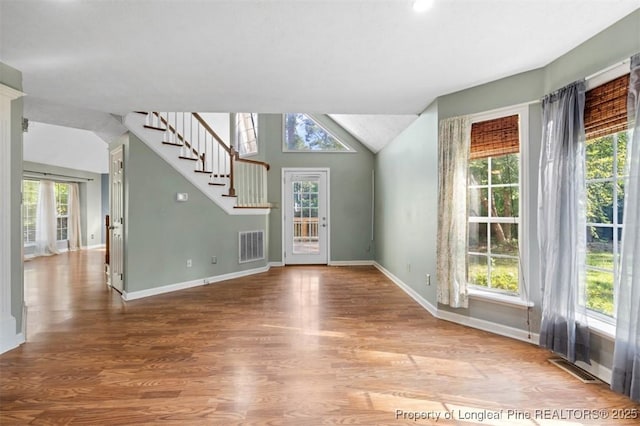 7616 Spurge Dr, Fayetteville, NC 28311 - unfurnished living room with plenty of natural light, wood finished floors, stairway, and vaulted ceiling