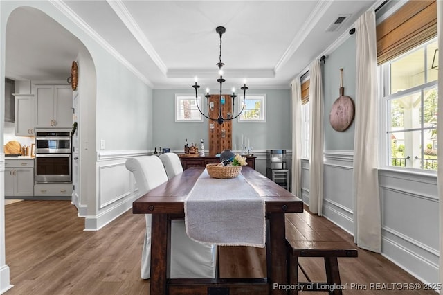 500 Legacy Lakes Way, Aberdeen, NC 28315 - dining room featuring arched walkways, a decorative wall, wood finished floors, a chandelier, and a raised ceiling