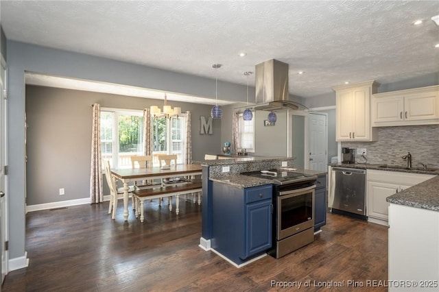 kitchen with stainless steel appliances, island exhaust hood, blue cabinets, a chandelier, and decorative backsplash