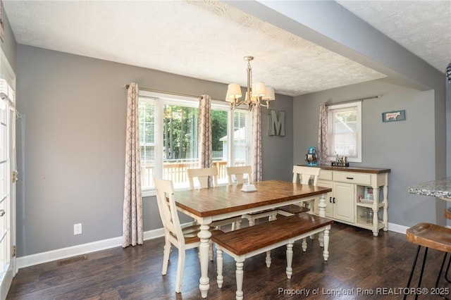 dining room featuring a chandelier, a textured ceiling, dark wood-style floors, and healthy amount of natural light