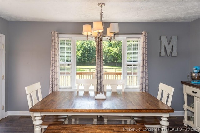dining area featuring a chandelier, plenty of natural light, wood finished floors, and a textured ceiling
