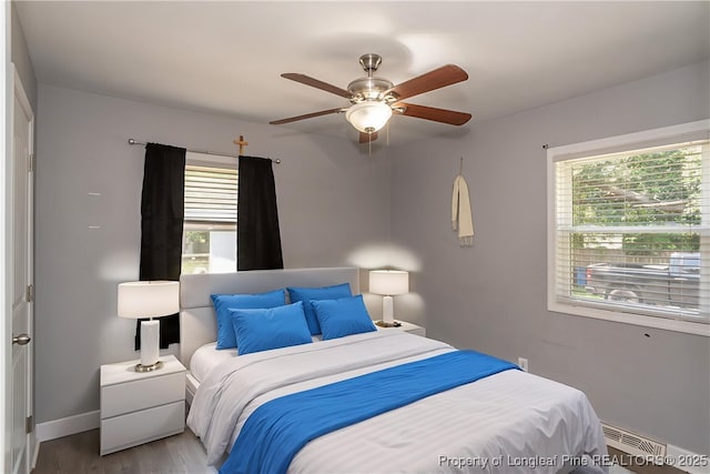 bedroom featuring wood finished floors, baseboard heating, and ceiling fan