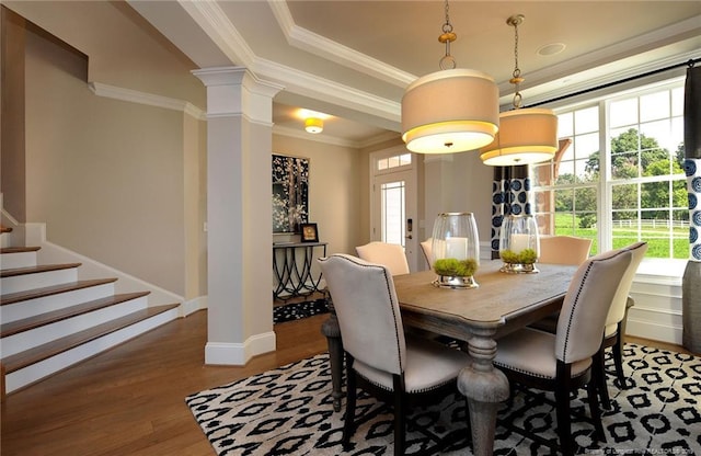 dining room featuring ornamental molding, ornate columns, a healthy amount of sunlight, and light hardwood / wood-style floors