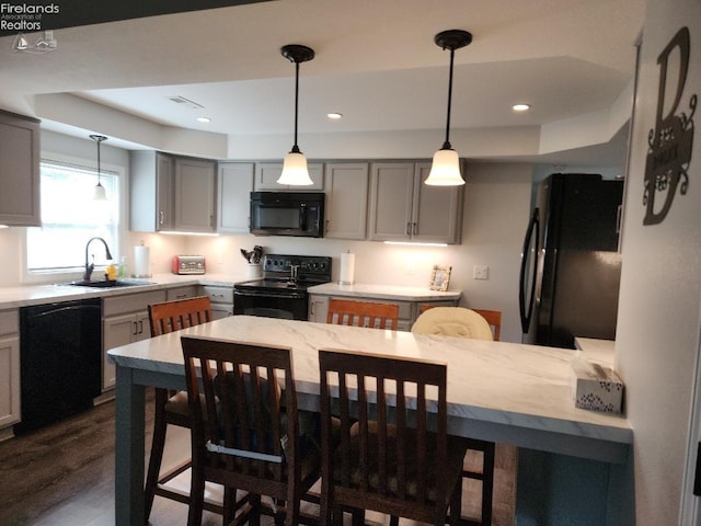 kitchen with gray cabinetry, black appliances, sink, dark hardwood / wood-style flooring, and pendant lighting