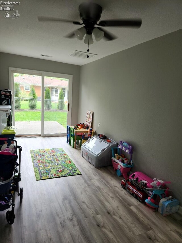 playroom with ceiling fan and light hardwood / wood-style flooring