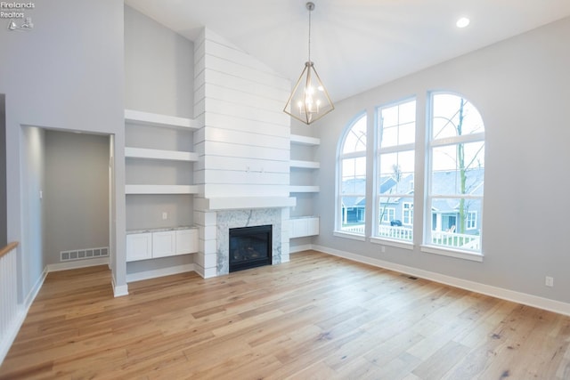 unfurnished living room featuring a fireplace, visible vents, baseboards, built in features, and light wood finished floors