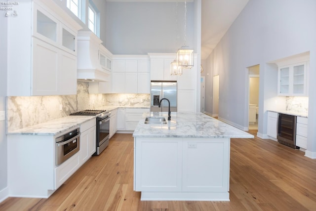 kitchen with appliances with stainless steel finishes, wine cooler, white cabinets, and glass insert cabinets