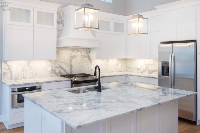 kitchen featuring glass insert cabinets, stainless steel appliances, decorative light fixtures, and white cabinetry