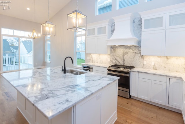 kitchen with a sink, white cabinets, custom exhaust hood, gas range, and glass insert cabinets