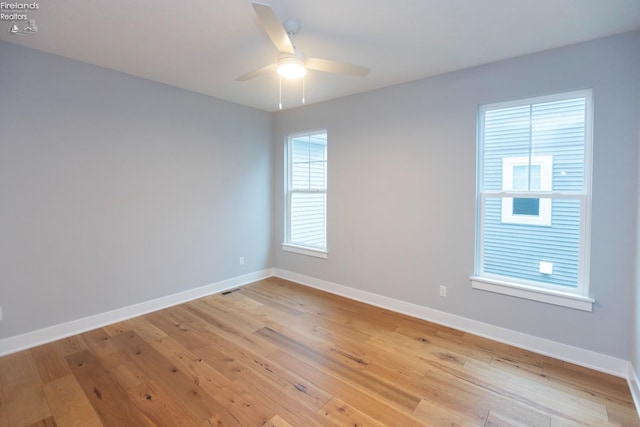 unfurnished room with light wood-style floors, visible vents, baseboards, and a ceiling fan