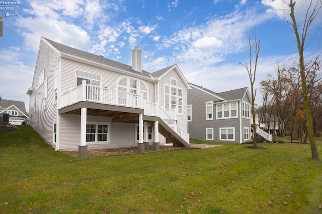 rear view of house with a chimney, a lawn, a deck, and stairs