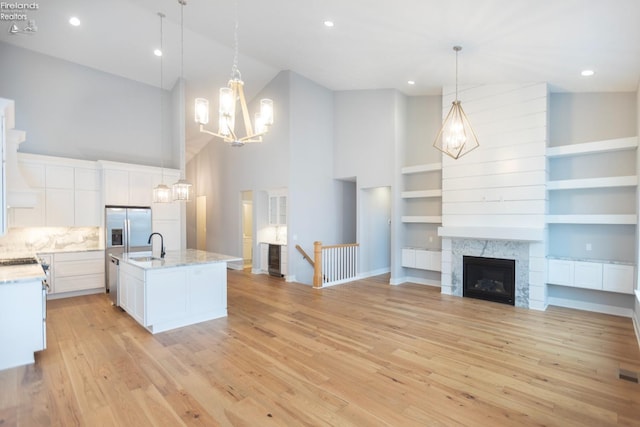 kitchen featuring open floor plan, pendant lighting, a center island with sink, and white cabinets