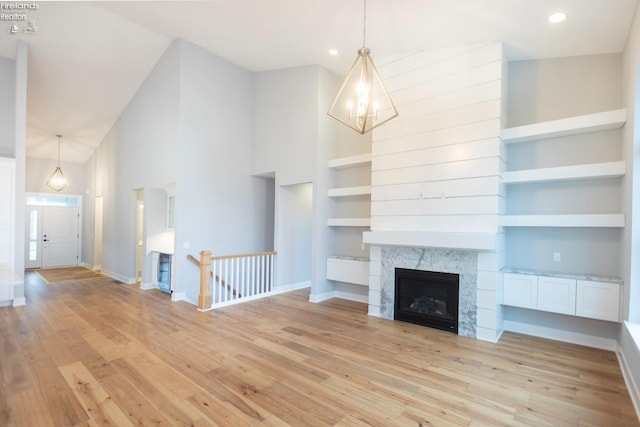 unfurnished living room featuring built in features, a fireplace, light wood-style flooring, and baseboards