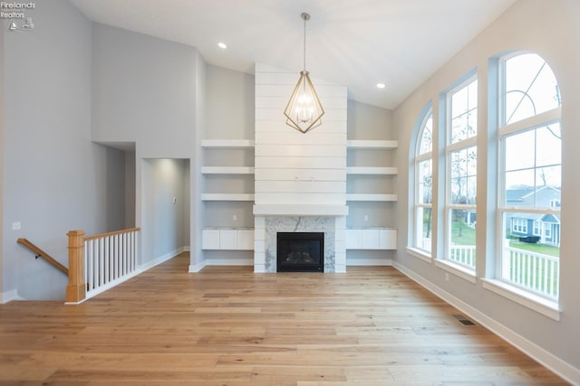 unfurnished living room with light wood finished floors, baseboards, visible vents, and built in features