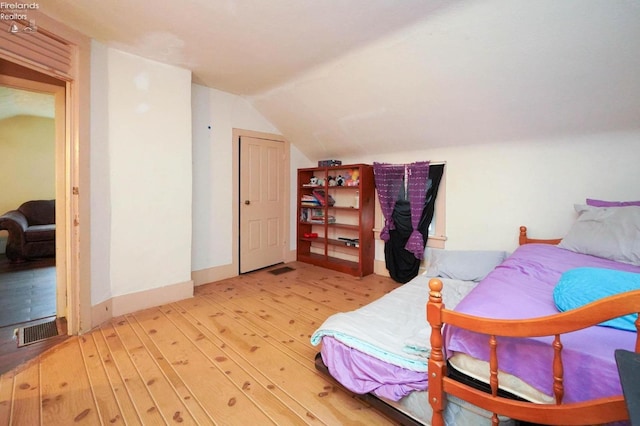 bedroom with lofted ceiling and light wood-type flooring