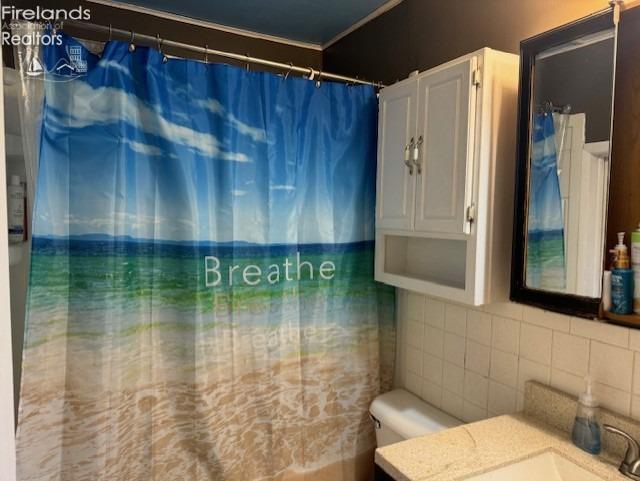 bathroom featuring tile walls, toilet, backsplash, and large vanity