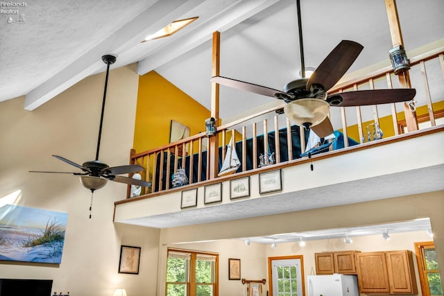 room details featuring a textured ceiling, white refrigerator, beamed ceiling, track lighting, and ceiling fan