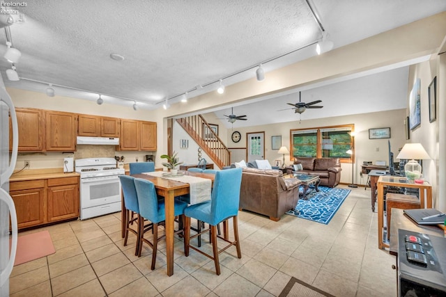 kitchen with ceiling fan, light tile floors, track lighting, and white stove