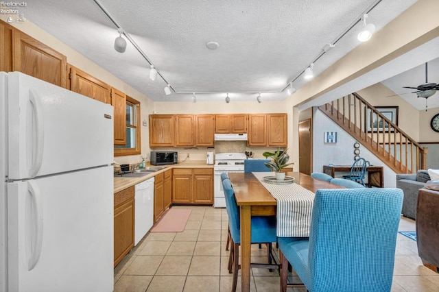 kitchen featuring light tile flooring, ceiling fan, track lighting, white appliances, and a textured ceiling