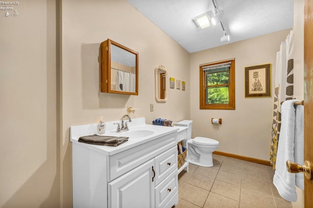 bathroom featuring rail lighting, a textured ceiling, toilet, and vanity